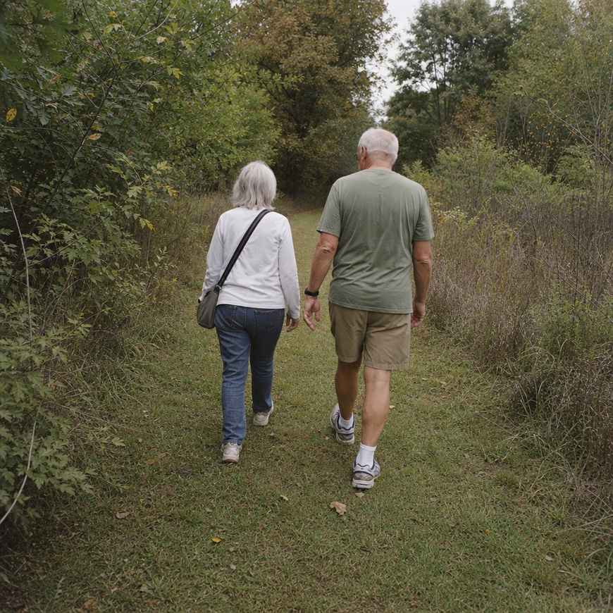 Two walkers keeping to the centre of a grassy path, away from the brushy overgrown edges